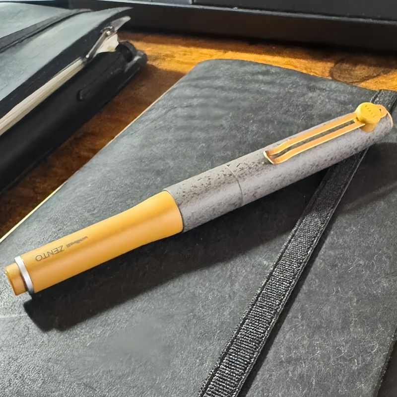 Gray and yellow Uni-ball ZENTO Signature magnetic gel pen on a notebook