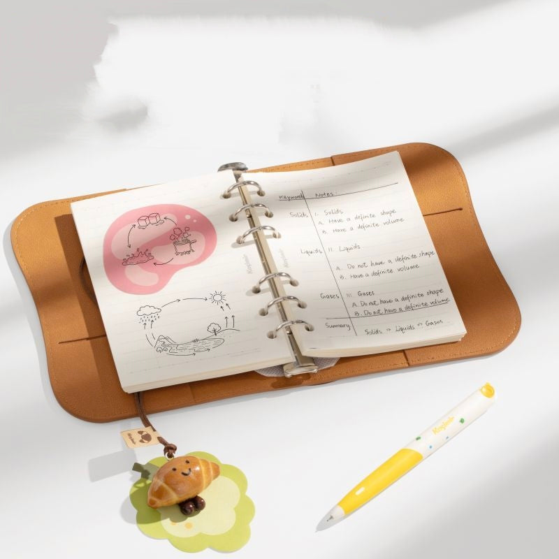 Kasimir notebook open with ring binder pages and charm